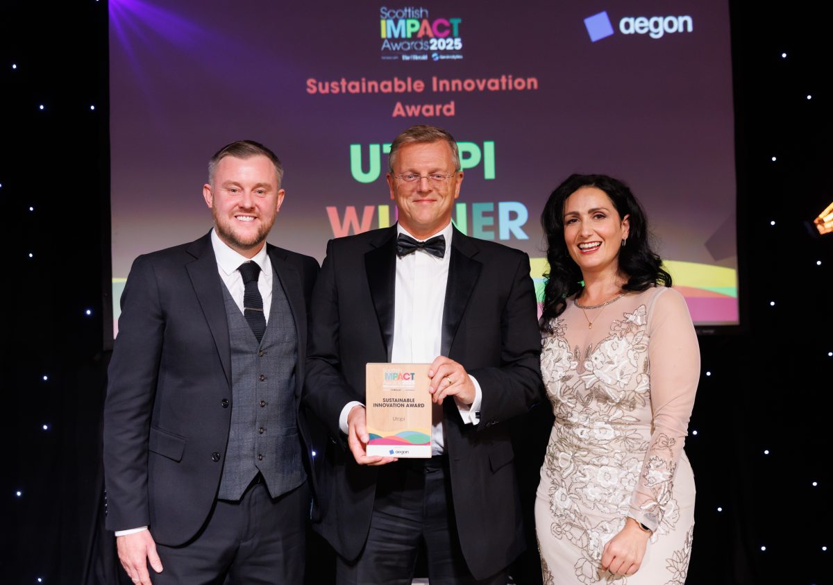 Two gentlemen in black tie stand with a woman in a formal dress holding an award.